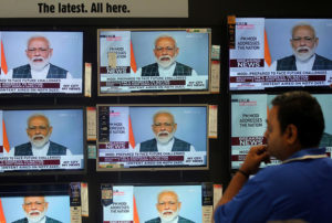 A Man Watches Prime Minister Narendra Modi Addressing To The Nation, On Tv Screens Inside A Showroom In Mumbai