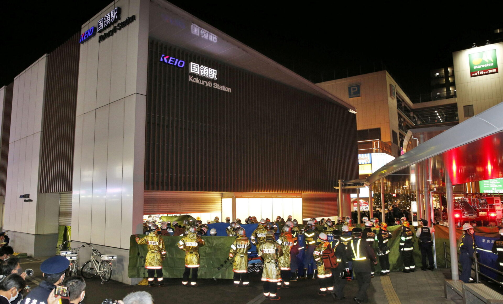 rescue workers and police officers work at the site where a knife and arson attack occurred on a train, at the kokuryo station of the keio line train in tokyo